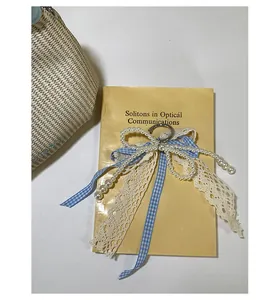 Dettaglio charm fiocco a quadretti blu con perle finte e pizzo su un libro