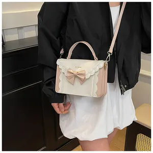 Close-up of a sweet bow detail and scalloped edge on a two-tone crossbody square bag