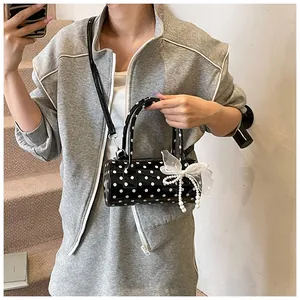 Detail einer schwarzen Polka-Dot-Zylindertasche mit Perlenquasten und Spitzenschleife