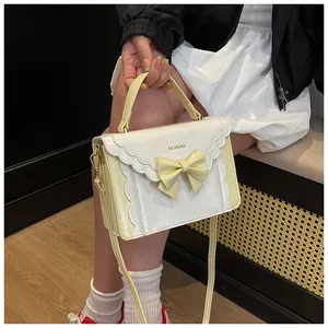 Detail of sweet bow decoration and wavy edges on cream and yellow crossbody bag