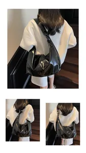 Detail of high-gloss wrinkled patent leather texture on a black hobo shoulder bag