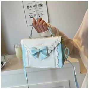 Detail of the bow decoration and scalloped flap on the light blue sweet crossbody bag