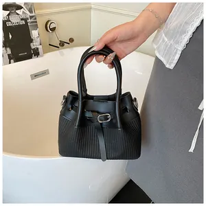 Detalle del bolso de cubo negro trenzado con cuero premium y hebilla metálica