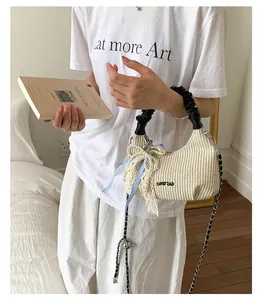 Dettaglio della trama intrecciata beige con catena di perle e fiocco a quadri blu