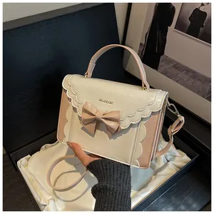 Detailed view of elegant bow handbag featuring wavy edge flap and brand logo in a gift box