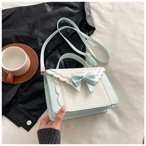 Detailed scalloped edges and bow knot on light blue and white crossbody flap bag