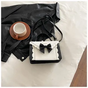 Detail of sweet bow-tie handbag with wavy edges on a stylish black leather backdrop