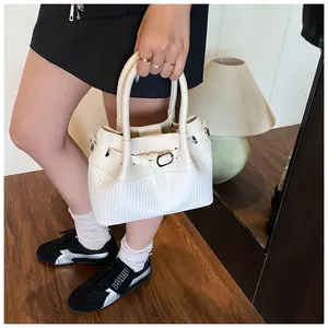 Detalle del bolso de cubo blanco en cuero trenzado con hebilla metálica en escena real