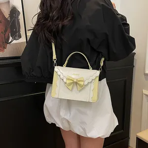 Chic cream and yellow accordion crossbody bag with bow detail and wavy trim finish