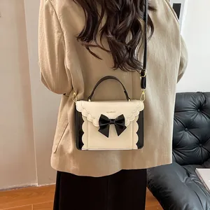 Chic cream and black accordion bag with bow detail and wavy flap shown on model