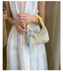 Dettaglio mini borsa in paglia beige con manico giallo e fiocco a quadretti azzurro