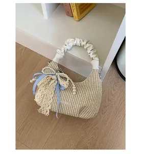 Dettaglio borsa intrecciata beige con manico a nuvola, perle e nastro di pizzo blu