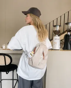 Bolso cruzado beige con colgante de felpa mostrado en un acogedor ambiente de café