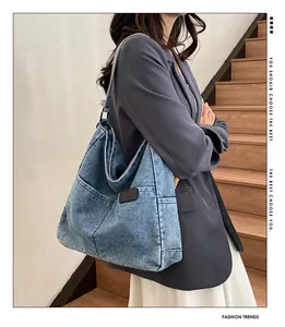 Detail of light blue denim tote bag with functional pockets and leather logo patch