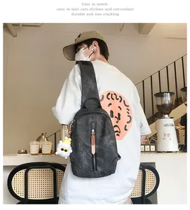 Dettaglio di una borsa a tracolla grigio scuro con zip verticale e ciondolo peluche