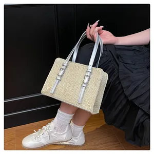 Close-up of woven straw handbag with silver metallic straps and buckle detail