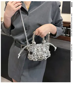 Dettaglio della borsa a secchiello argento con perle metalliche e chiusura a coulisse
