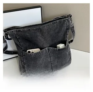 Detail of dark grey denim tote bag with functional front pockets for phone and charger