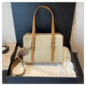 Detail of woven straw handbag with leather straps in a premium black gift box