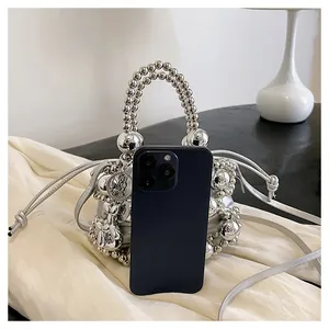 Mini borsa a secchiello con perle argento accanto a smartphone per la taglia