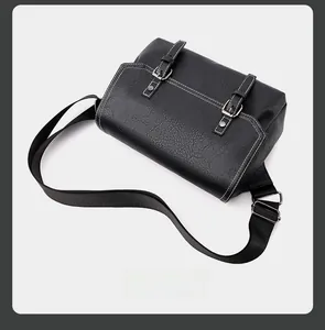 Detail of black PU leather messenger bag with white stitching and double metal buckles