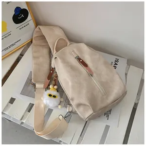 Dettaglio borsa a tracolla in tela con tirazip in pelle e ciondolo peluche bianco