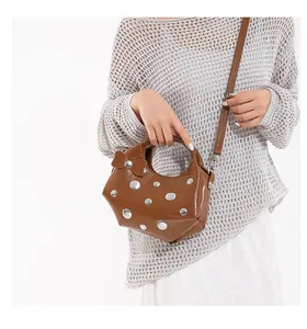 Detail of dark brown studded underarm bag with glossy finish and silver rivet accents