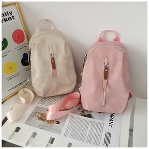 Dettaglio di mini zaini in tela beige e rosa con cerniere in metallo e finiture eleganti