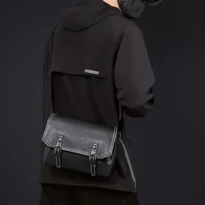 Men's black PU messenger bag with buckle detail and adjustable strap on a model
