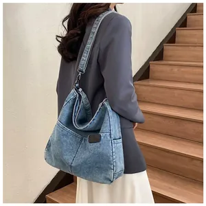 Detail of blue denim tote bag side pocket and leather patch on washed fabric