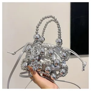 Dettaglio della borsa a secchiello argento con perle metalliche e chiusura a coulisse