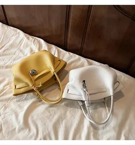 Close-up of yellow and white litchi leather handbags with silver bean metal charms