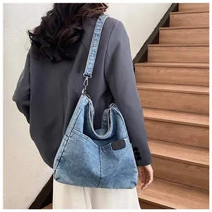 Detail of blue denim tote bag with vertical stitching and wide strap on model