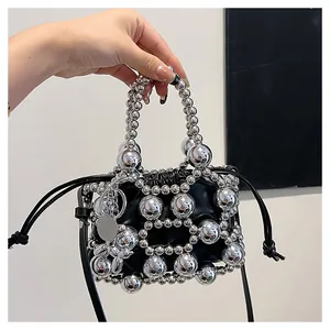 Dettaglio borsa a secchiello con perline metalliche argentate e tracolla in pelle nera