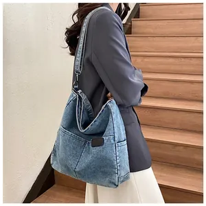 Detail of blue denim tote bag showing side pocket, adjustable strap and metal hardware