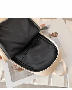 Vista interior de la mochila beige con forro gris de marca y compartimento con cremallera