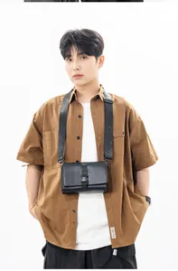 Men's minimalist black crossbody box bag with buckle closure on casual brown shirt