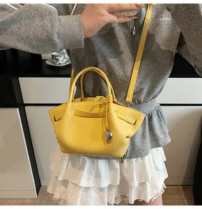 Close-up of bright yellow leather tote bag with silver charm and adjustable strap detail