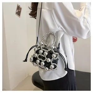 Dettaglio borsa a secchiello con sfere di metallo argento e sacchetto interno con coulisse