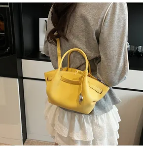 Detail view of small yellow tote bag featuring pebble grain leather and wing side design