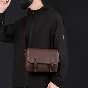 Detail view of dark brown PU messenger bag with contrast stitching and metal buckles