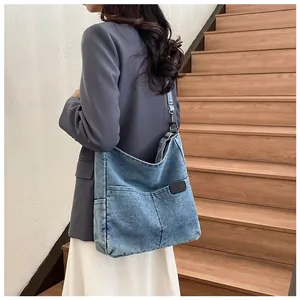 Close-up of washed denim tote bag with functional front pocket and leather logo tag
