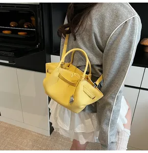 Detail of yellow lychee grain leather tote bag with dual handles and silver pendant