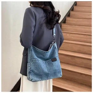 Detail view of denim tote bag with functional front pockets and leather logo label