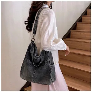 Detail of a large charcoal denim tote bag with washed texture on a female model