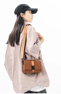 Brown leather crossbody box bag with nylon strap and black plastic buckle detail
