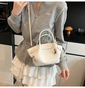 Close-up of white lychee leather mini tote bag with silver heart charm and crossbody strap