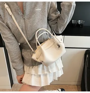 Detail of white litchi grain leather wing tote with heart pendant and silver hardware