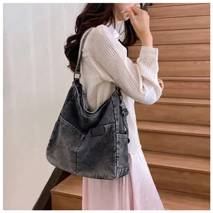 Detail of large charcoal denim hobo bag with vintage wash and exterior pocket