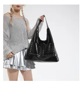 Detail of black glossy tote bag featuring silver hexagonal rivets on two front pockets